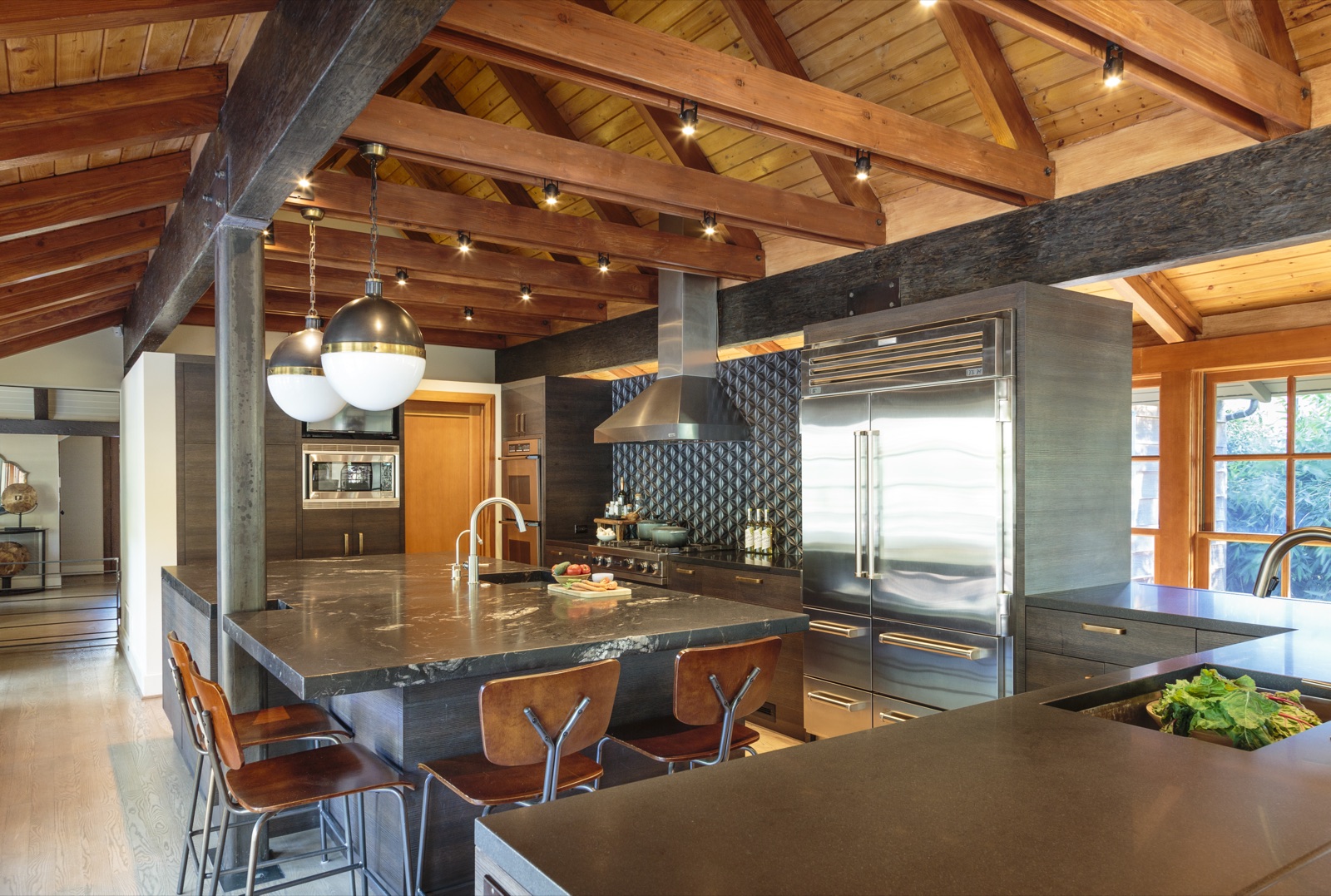 Brentwood Layton Drive custom kitchen by ESRL Development, vaulted timber-truss ceiling with exposed rough-sawn beams, twin soapstone-topped islands, Sub-Zero column refrigerator, stainless range with custom hood, mosaic backsplash and walnut barstools.