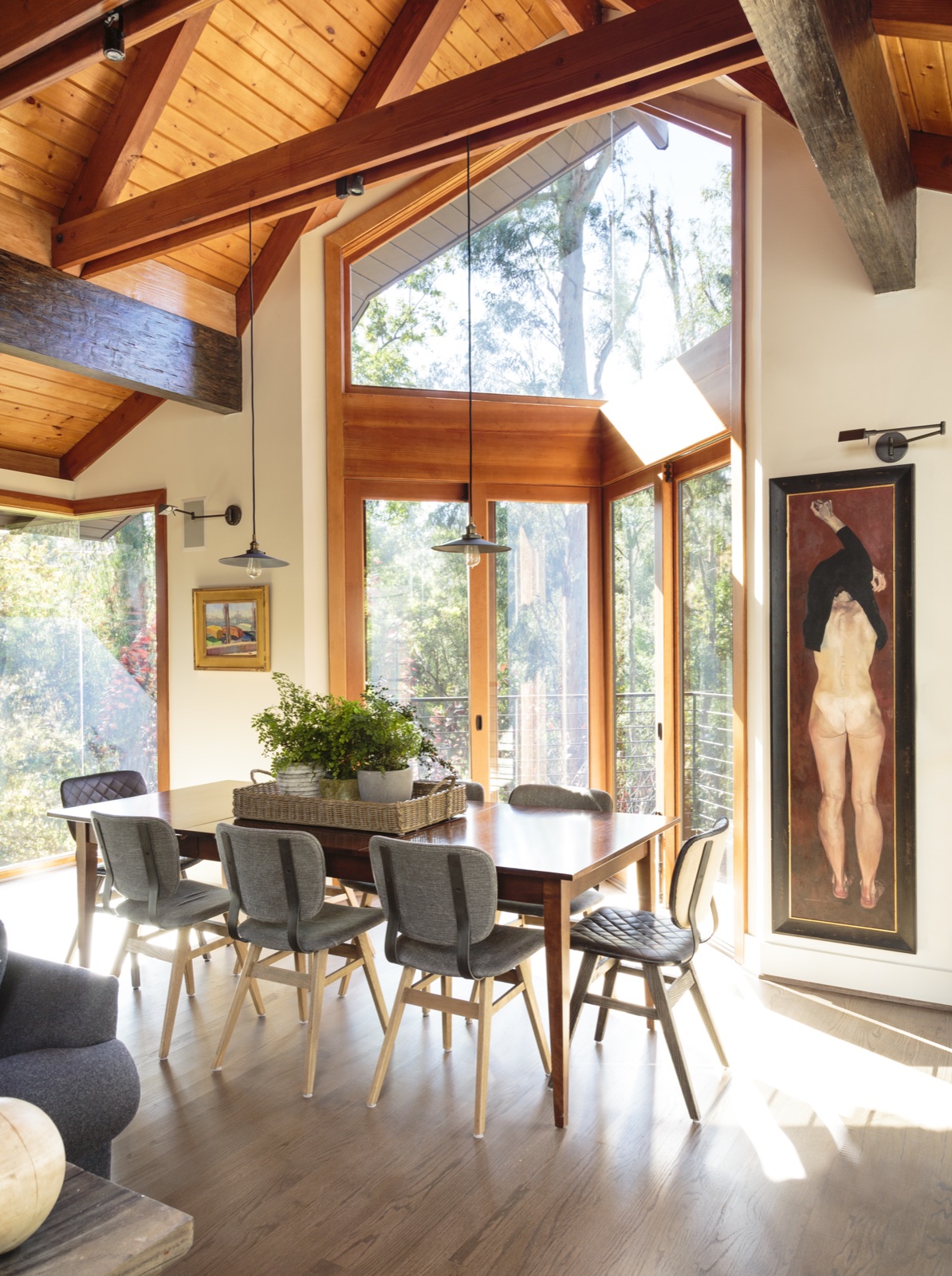 Dining area in the Brentwood Layton Drive residence, soaring gable window framing the canyon, walnut dining table, vaulted cedar ceiling, cable-rail balcony. ESRL Development.