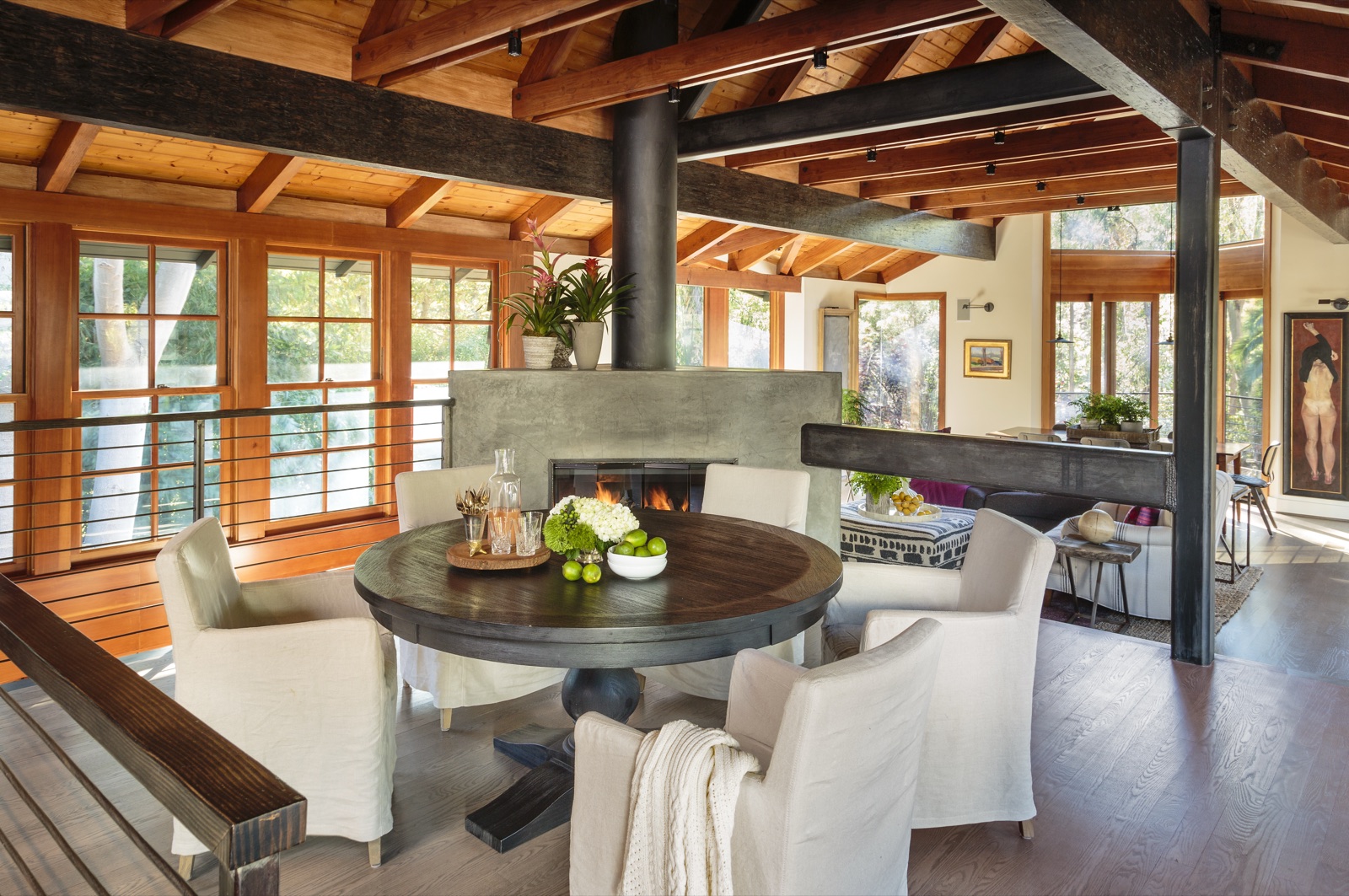 Brentwood Layton Drive round dining nook with custom blackened-steel double-sided fireplace surround, exposed timber ceiling, banquette and cable-rail walkway. Custom residence by ESRL Development.