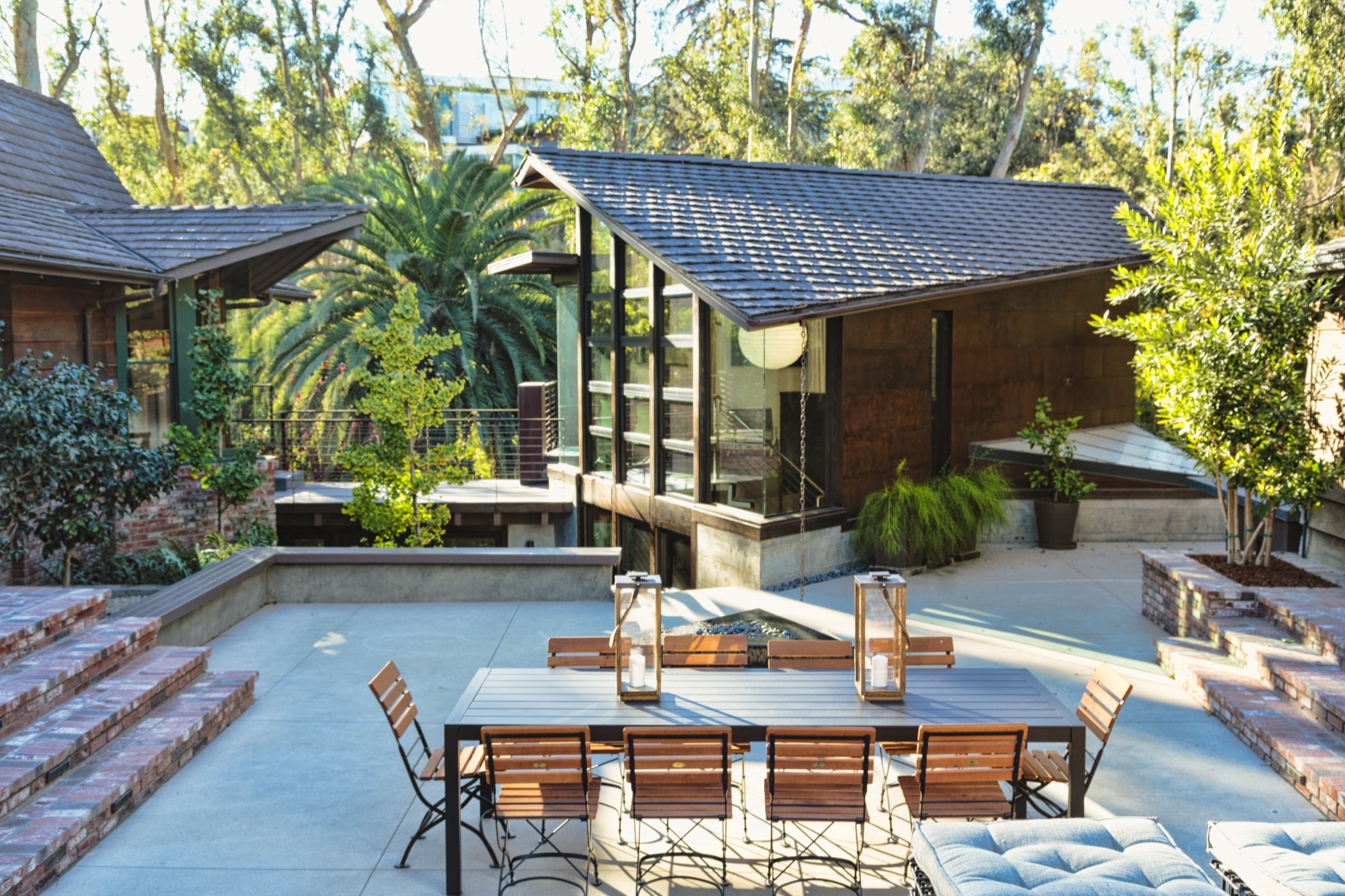 Brick-paved courtyard between the original cedar wing and the new glass-and-steel pavilion in the Brentwood Layton Drive residence, alfresco dining for ten, hand-laid brick, walled garden, mature canyon trees. ESRL Development.