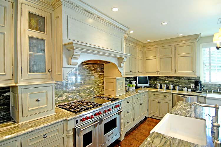 Luxury kitchen with custom range hood, Wolf range, dramatic veined marble countertops and backsplash, traditional cream cabinetry. Hollywood Hills.