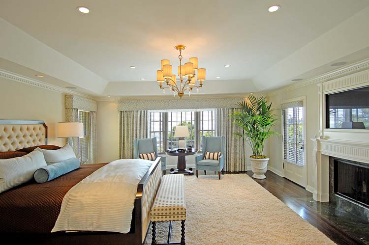 Master bedroom with tray ceiling, custom fireplace, traditional luxury furnishings. Hollywood Hills.