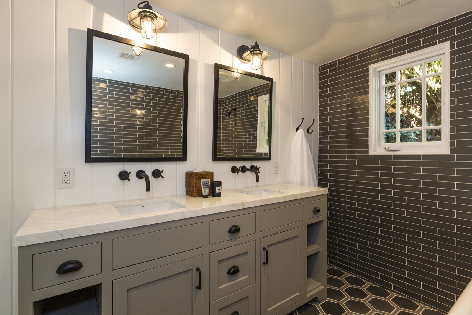 Master bath double vanity at 855 Jacon Way Pacific Palisades, soft-grey shaker base, marble counter with twin undermount sinks, framed mirrors, matte-black wall-mounted bridge faucets, industrial cage sconces and a shiplap ceiling overhead. ESRL Development.